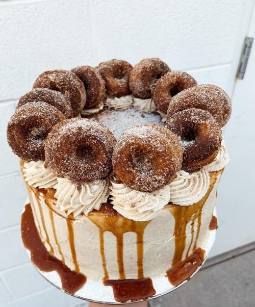 vegan cake covered in vanilla butter cream, caramel drizzel and topped with mini cinnamon sugar donuts from the bite club in nashville