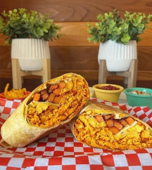 vegan breakfast burrito cut in half and sitting on a white and red checker napkin at green leave vegan in LA