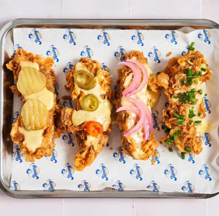 a lineup of vegan chick'n strips topped with creamy cheese, sauces, pickles, onions and more in paris