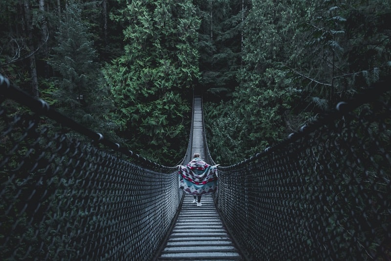 the lynn canyon suspension bridge with one person in the middle at dusk on a vancouver day trip