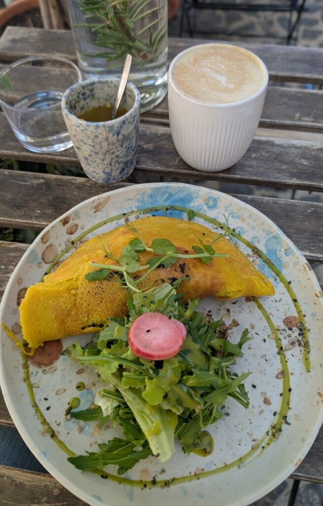 a vegan omelet next to a small green salad and coffee on an outdoor table at mothers daughter in lisbon 