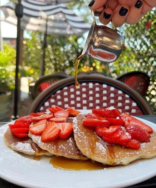 a stack of vegan pancakes topped with syrup and strawberries at pura vita in LA