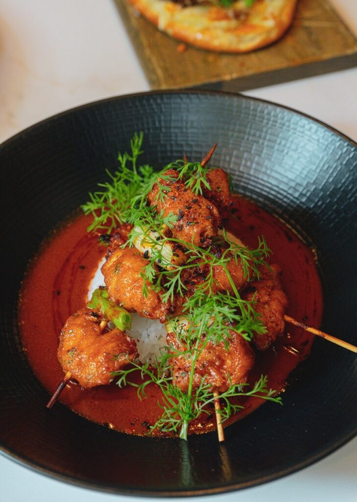 upclose shot of fried vegan croquettes in a tomato sauce topped with fresh herbs at reverie
