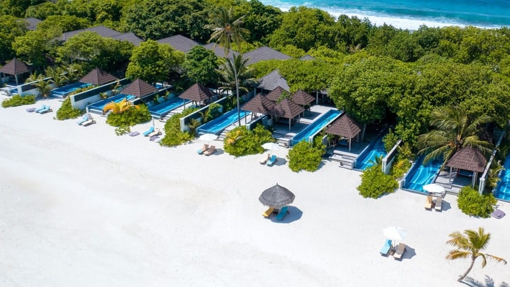 ariel overview of the white sand beach and private bungalows at the vegan-friendly resort Atmosphere Kanifushi in the maldives