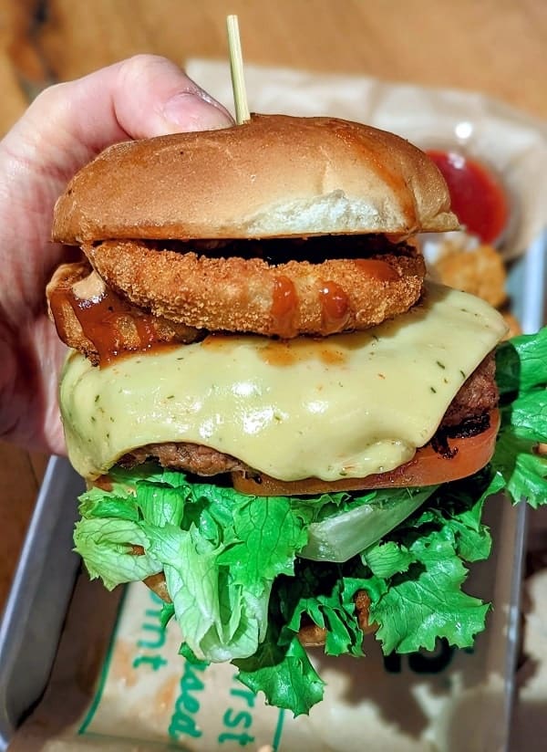 giant vegan burger with cheese and onion rings from the vegan fast food joint next level burger