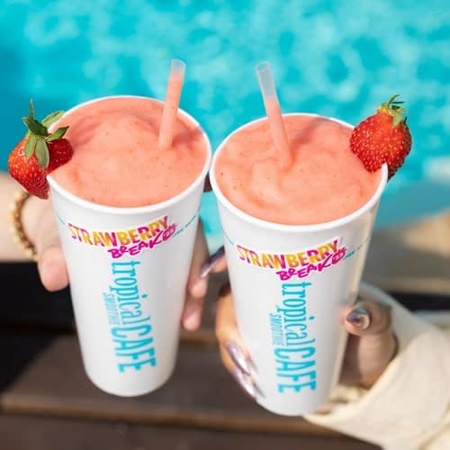 two strawberry smoothies next to a pool from tropical smoothie cafe