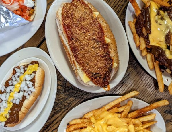 spread of vegan fast food options like cheese covered fries, chili cheese dog, chicken parm sandwich