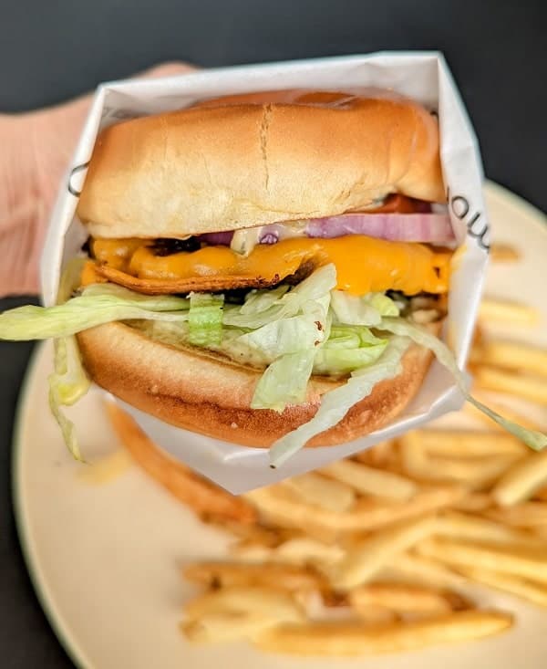 vegan burger held over french fries at the veggie grill vegan fast food restaurant 