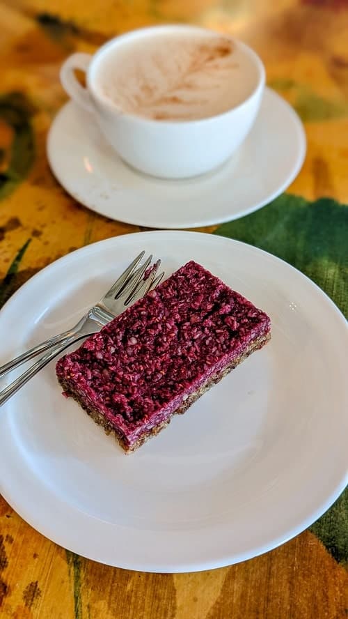 raw vegan berry cake on a white plate in front of a chai tea in akureyri iceland