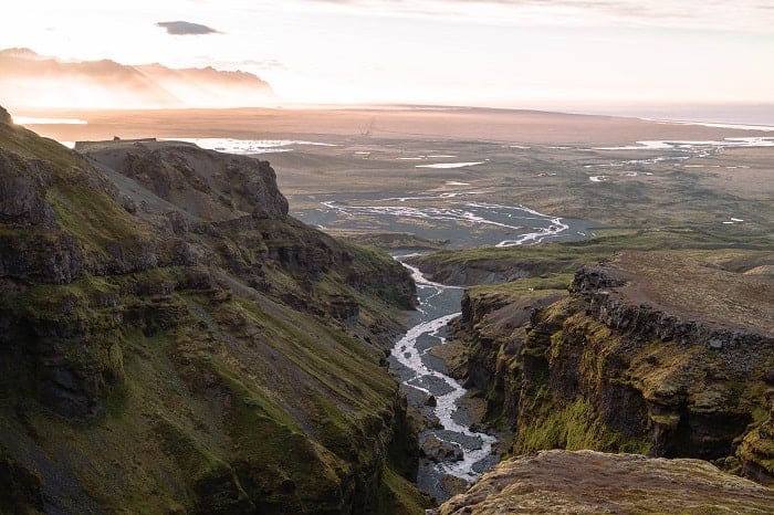 the Múlagljúfur Canyon with a river running through it on a hazy day at sunset in iceland