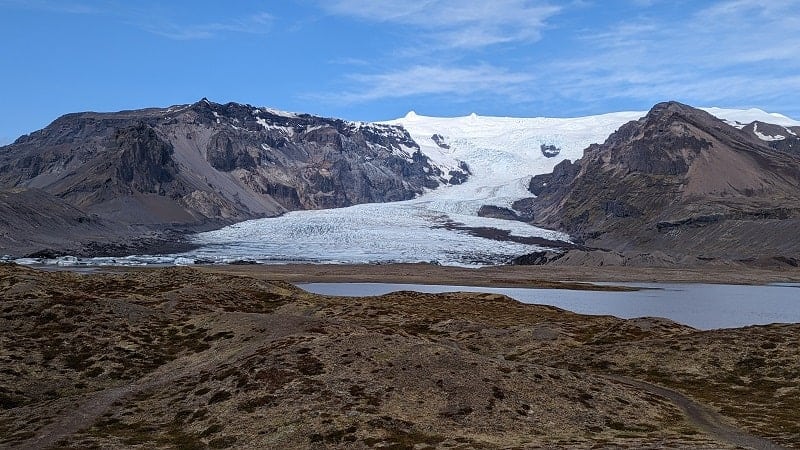 Vatnajokull glacier peaking out between two brown mountain peaks in iceland