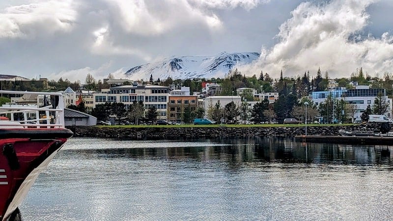 akureyri harbor with snow covered mountain peaking through cloud cover on an iceland ring road tour