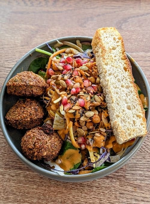 chickpea vegan falafel salad bowl topped with pomegranate seeds and a slice of fresh bread in Reykjavik