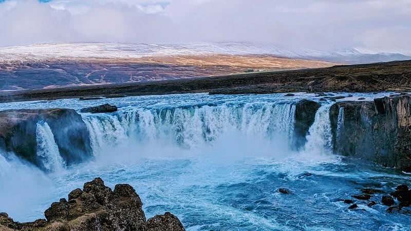 godafoss waterfall in a horseshoe shape early in the morning with the sun low in the background in iceland on a g adventures tour