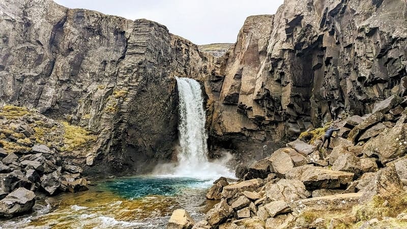 hidden waterfall flowing into a blue pool found off of the highway in Iceland on a G adventures tour