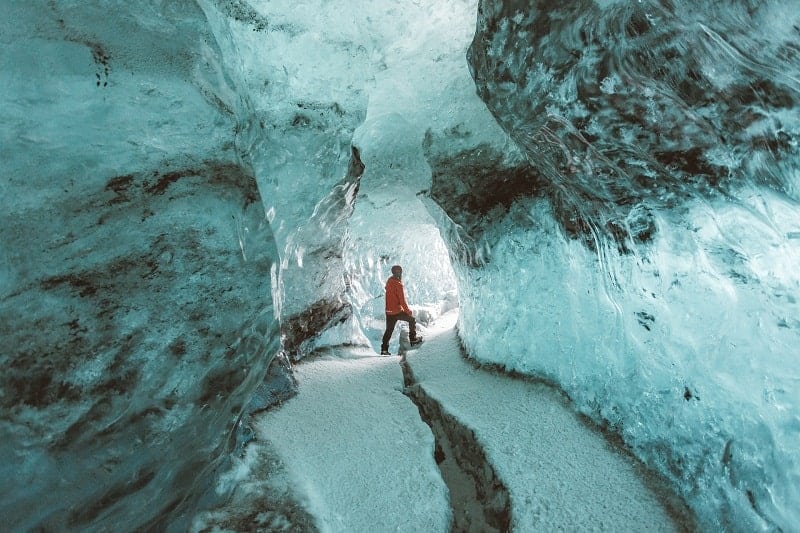 white and black colored ice cave with a person standing in the middle in iceland