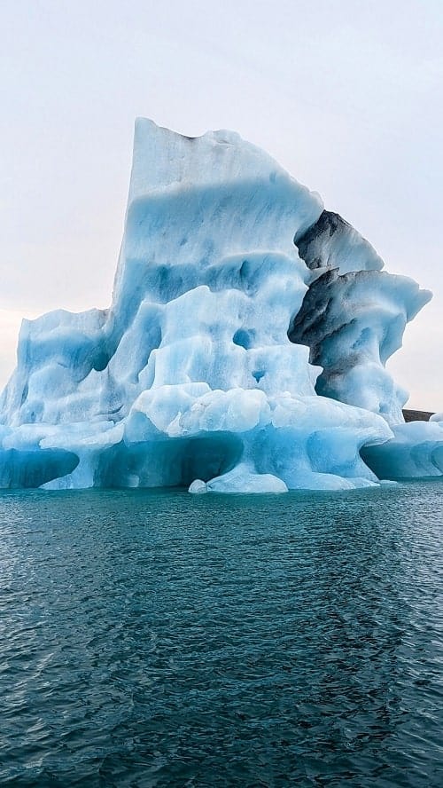 massive blue, black, and white iceberg in the jokulsarlon