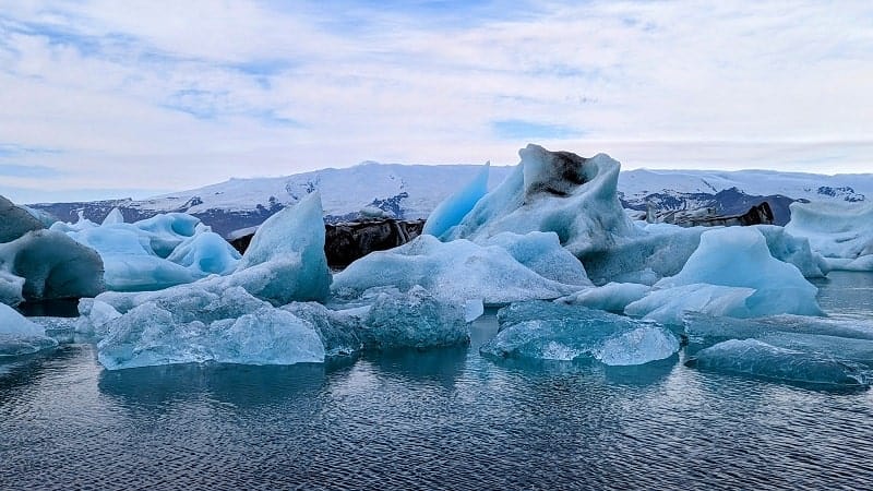 blue, white and black icebergs floating in the jokulsarlon glacier lagoon in iceland