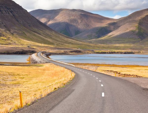 iceland ring road self drive tour with the road curving over water and into a mountain pass