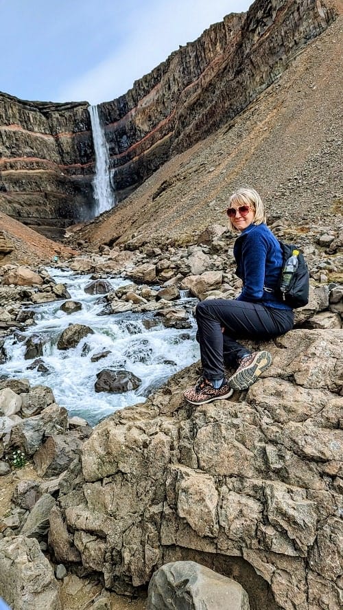 rebecca gade sawicki sitting on a rock  at the Hengifoss waterfall on a g adventures tour in iceland