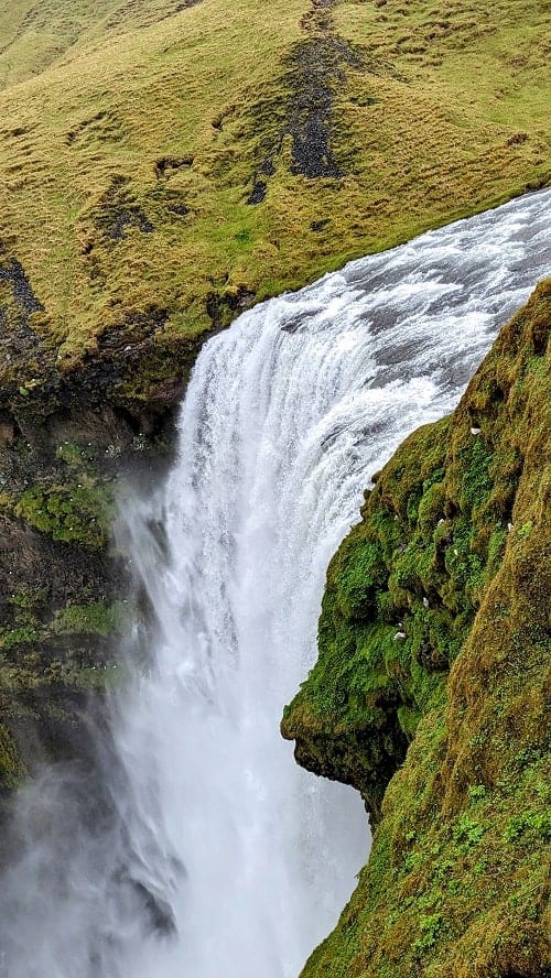 the skogafoss waterfall viewed from above with water rushing over the cliff