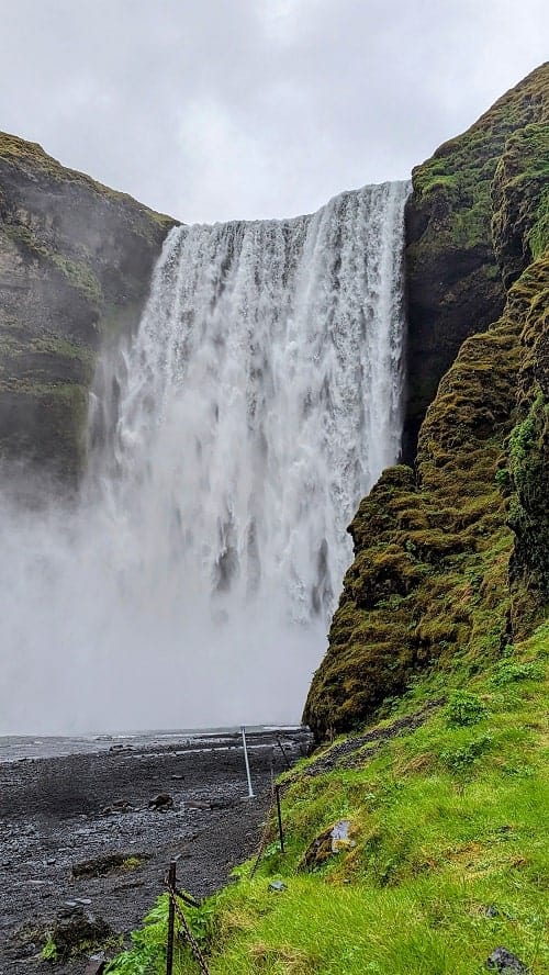 the skogafoss waterfall at the foot of the waterfall with water spraying at the ground