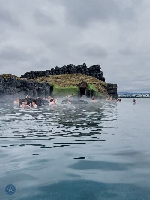 the geothermal pool with people hanging near the cliff at the sky lagoon in Reykjavik 