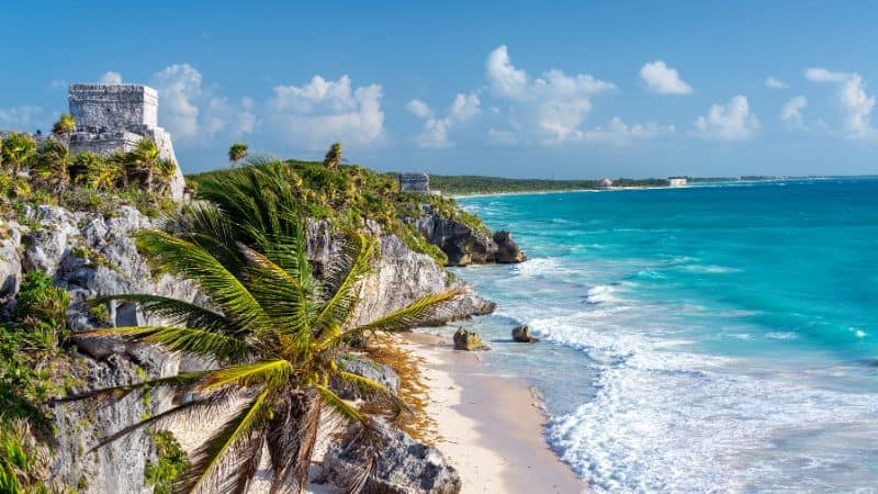 mayan ruins on a cliff overlooking the beach and turquoise blue waters in tulum 