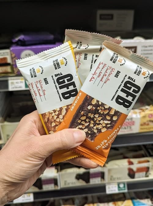 three gluten free bar protein bars in a person's hand which are good vegan travel snacks