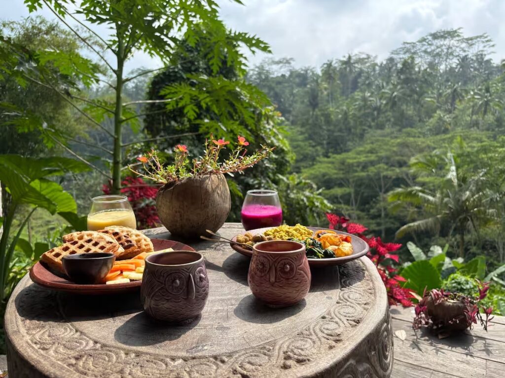 vegan breakfast spread on an outdoor table overlooking a lush valley in bali