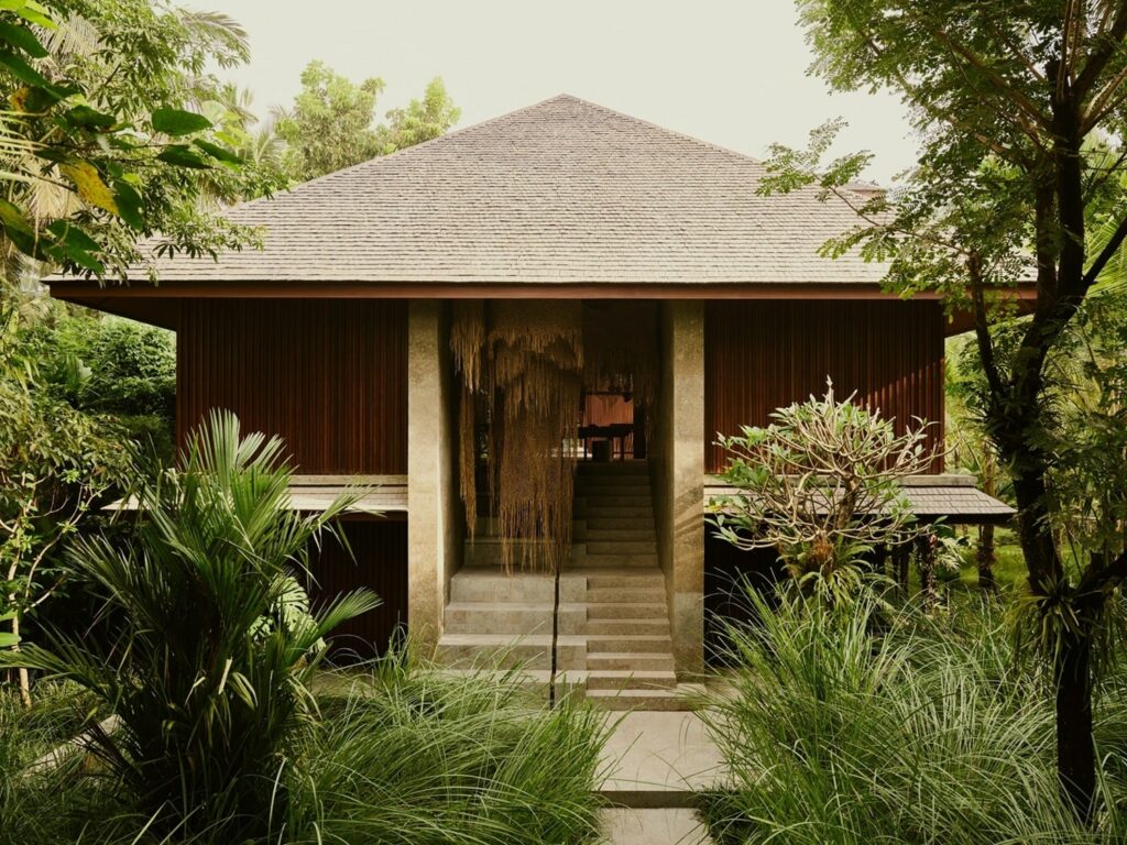 the front entrance to an open air Balinese bungalow tucked into lush greenery in bali 