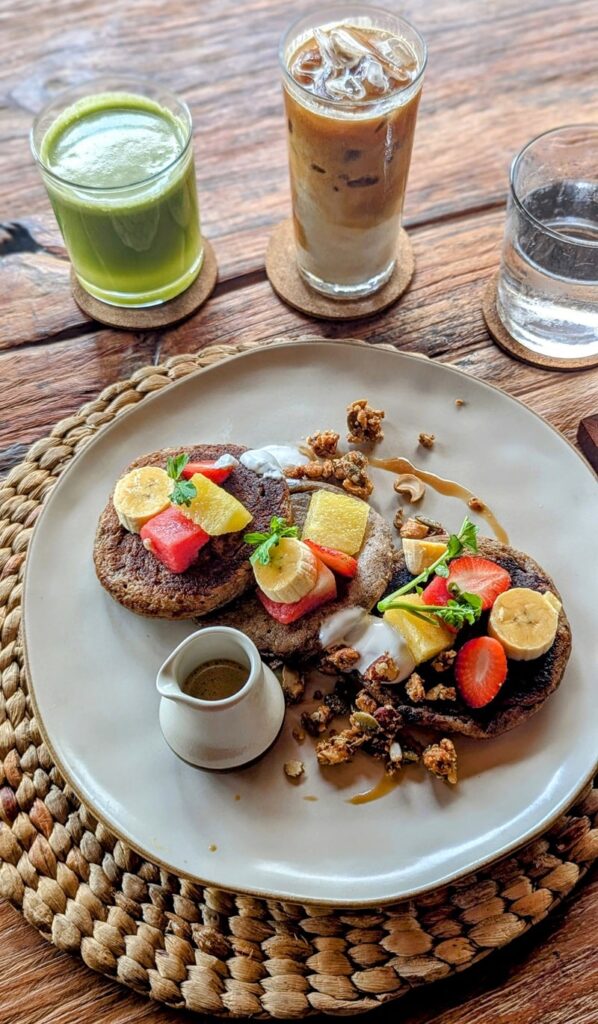 a stack of vegan pancakes next to a coffee and green smoothie at asa maia in bali