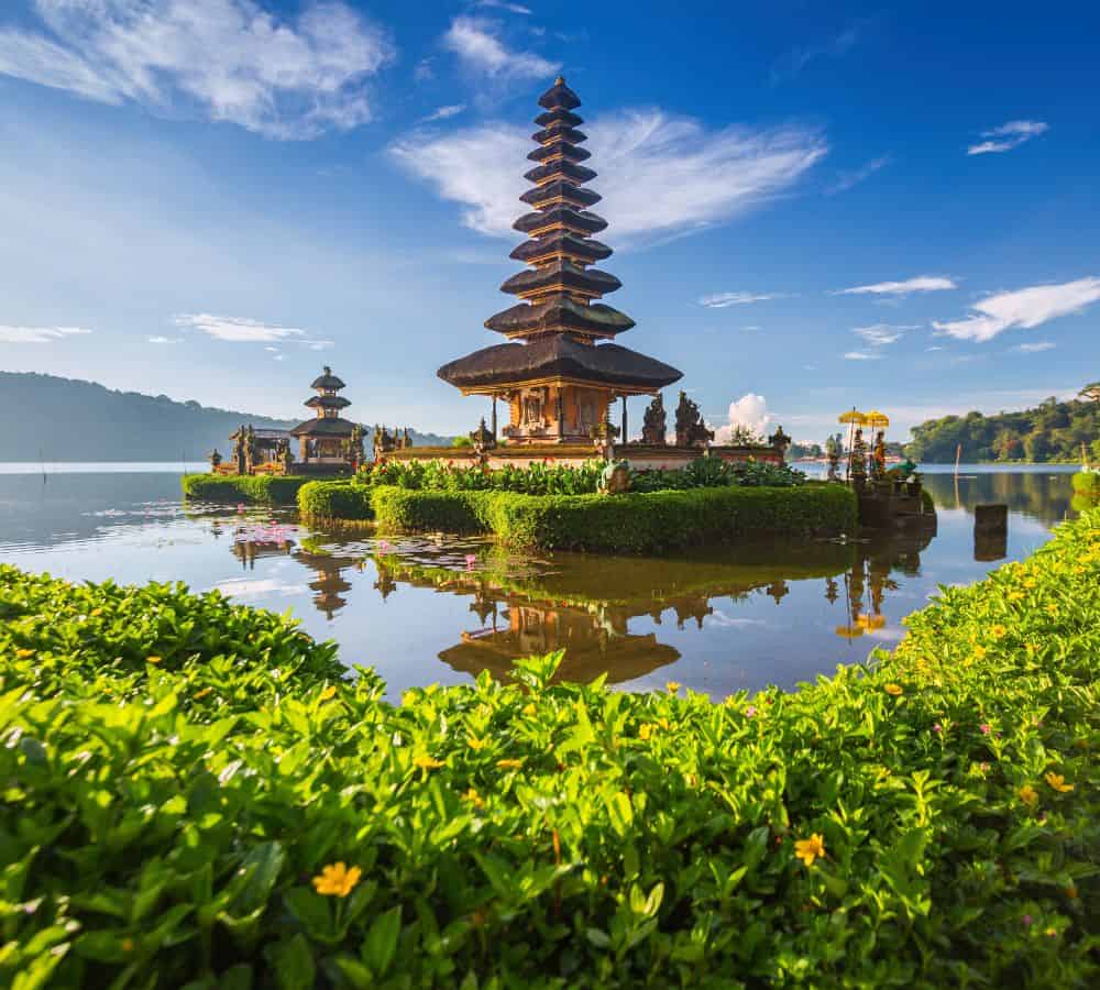 large Balinese temple surrounded by water and lush greenery in bali