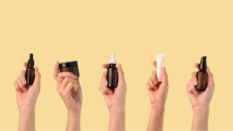 liquid beauty products held up in peoples hands that you dont want to pack in your carry on