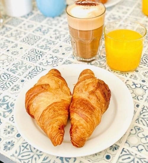 two vegan croissants on a plate next to juice and coffee at cloud cakes vegan cafe in paris