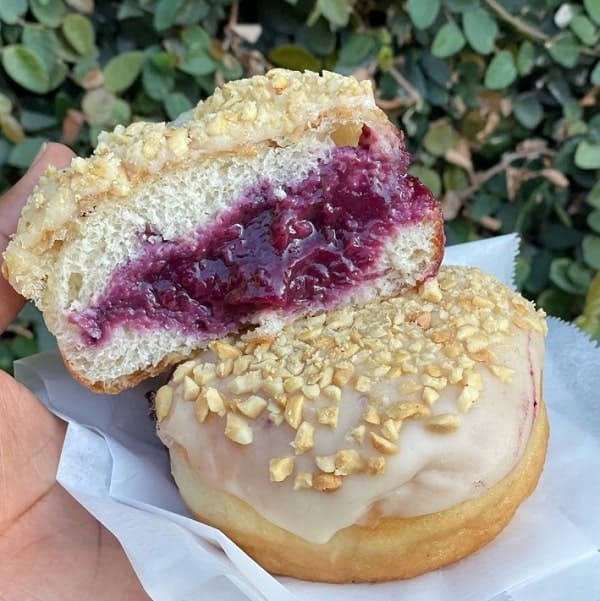 vegan peanut butter and jelly donut cut in half showing the blueberry jelly from devi's donuts in los Angeles 