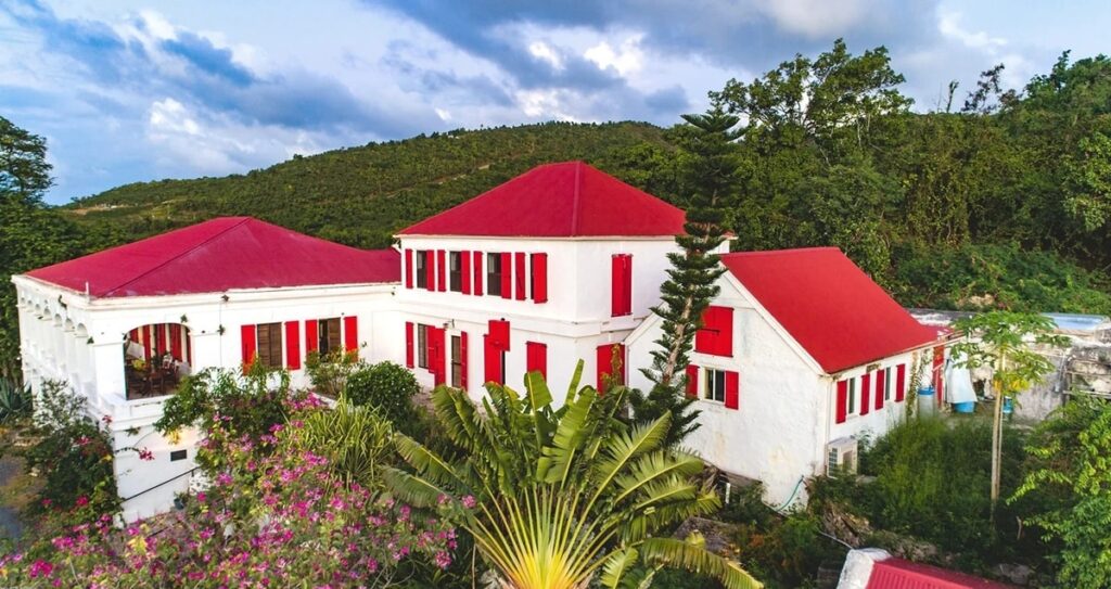 the main guesthouse with a white exterior and red roof at the feather leaf inn in st croix