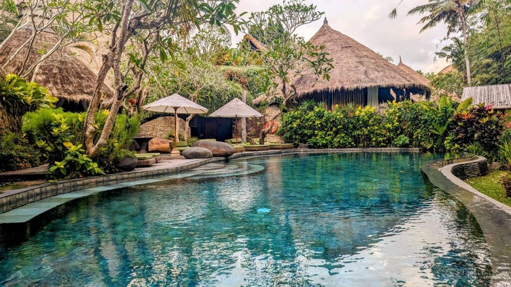 large pool overlooking the river and surrounded by thatched buildings and jungle at fivelements retreat in bali