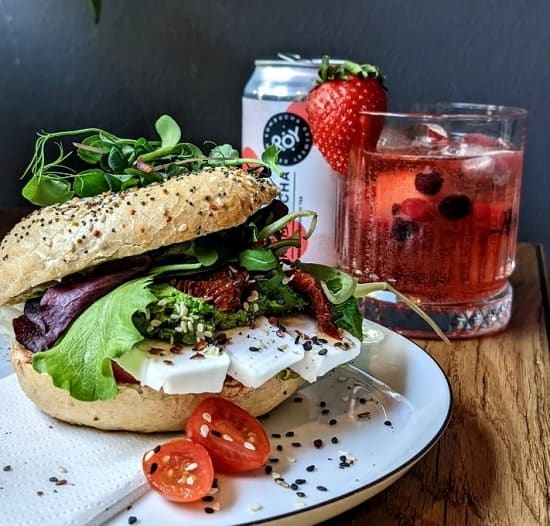 vegan breakfast bagel sandwich next to a pink drink at geh veg in berlin