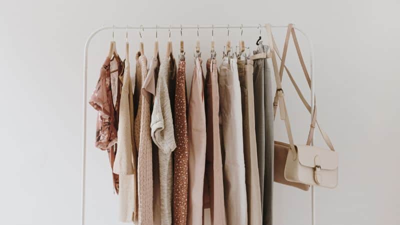 neutral clothing hanging on a rank in front of a blank wall