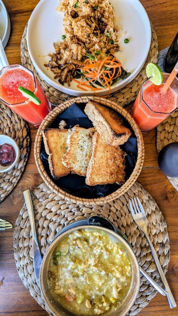 overhead shot of a vegan breakfast spread with colorful juices, a bread basket, and two large entrees at wapa di ume