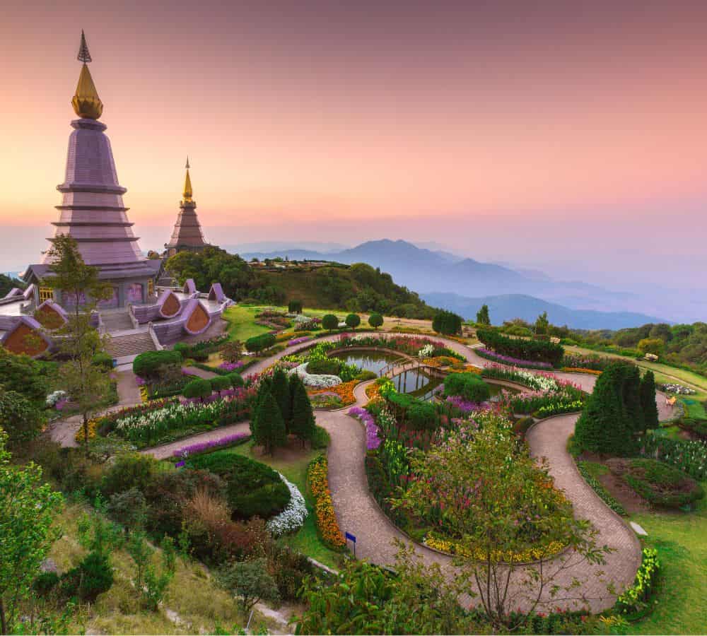 Doi Inthanon National Park with a temple in the background surrounded by gardens at sunrise with a pink an purple sky