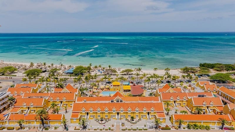 overhead view of the yellow and orange colored vegan-friendly resort amsterdam manor along the water in aruba