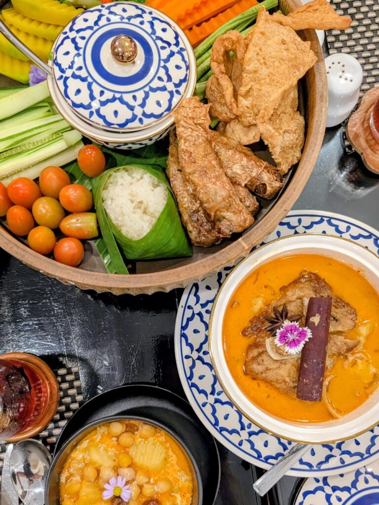 vegan curry, appetizer, and more in colorful blue bowls spread on a table at the vegan hotel away chiang mai in thailand