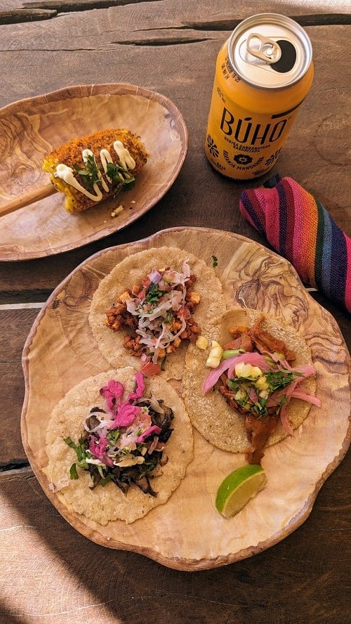 a plate of three colorful vegan tacos next to a small cob of corn covered in spices and cream at the palmaia resort in playa del carmen