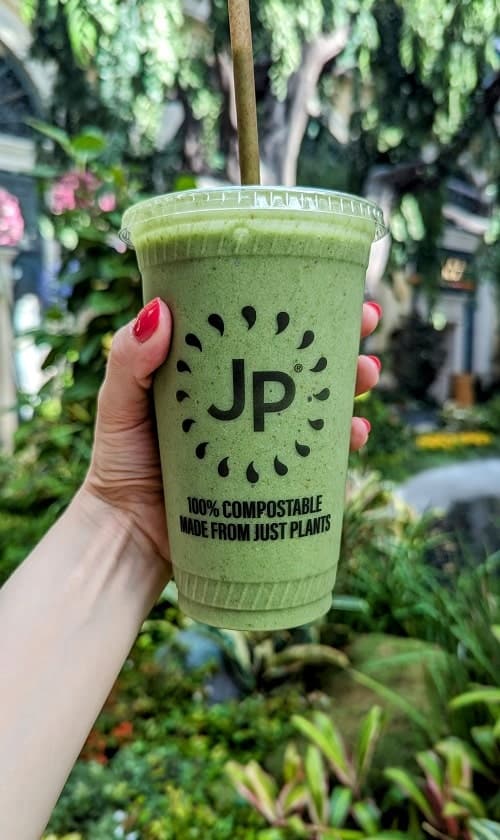 green smoothie held in front of the Bellagio gardens from juice press in las vegas