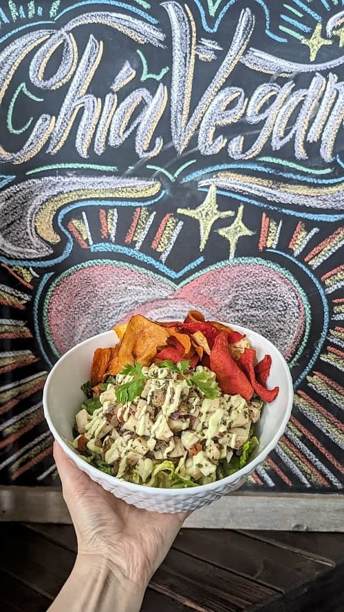 vegan ceviche salad with colorful taro chips in front of a chalk board sign for the west palm beach restaurant la chia vegana