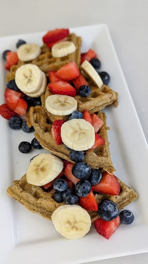 vegan and gluten free waffles covered in berries and banana slices on a white plate at meraki juice kitchen in west palm beach