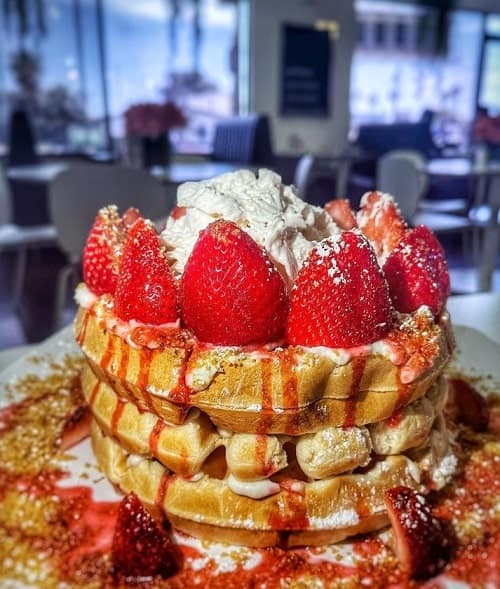 stack of golden vegan waffles topped with strawberries and whipped cream from the modern vegan in las vegas