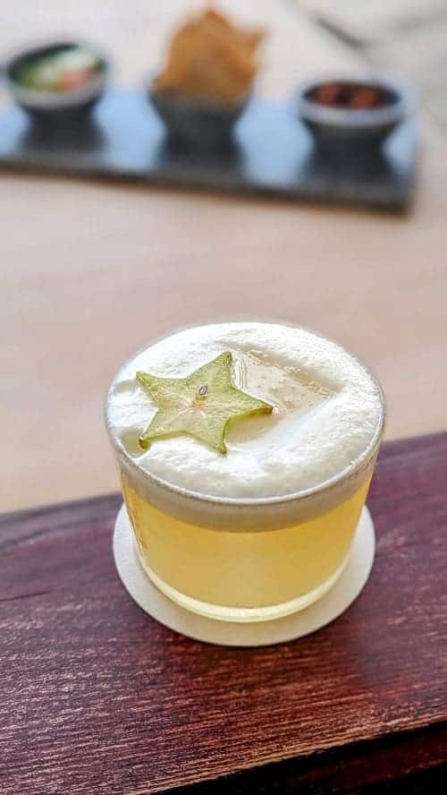 a yellow pineapple cocktail topped with foam and a starfruit at the palmaia resort in playa del carmen